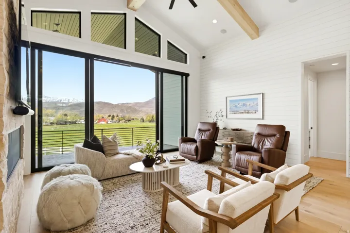 Living area with a mountain view, light wood-style floors, wooden walls, vaulted ceiling, and recessed lighting