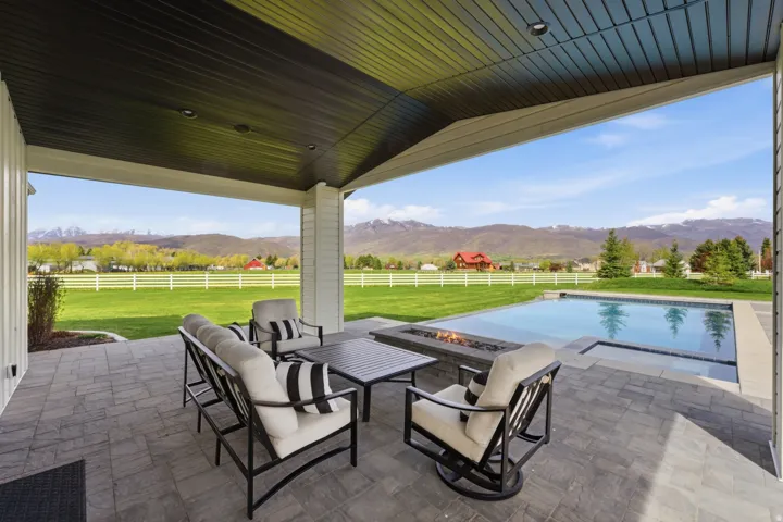 Fenced backyard with a mountain view, a patio, an outdoor living space with a fire pit, a view of rural / pastoral area, and an outdoor pool