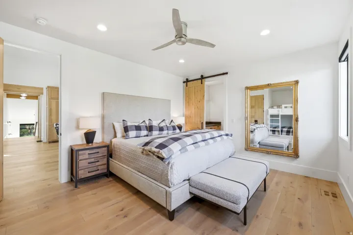 Bedroom featuring a barn door, light wood-style flooring, a ceiling fan, recessed lighting, and multiple windows