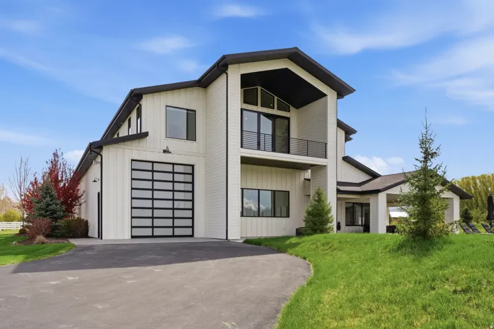 View of front of home with a balcony, driveway, a front lawn, and a garage