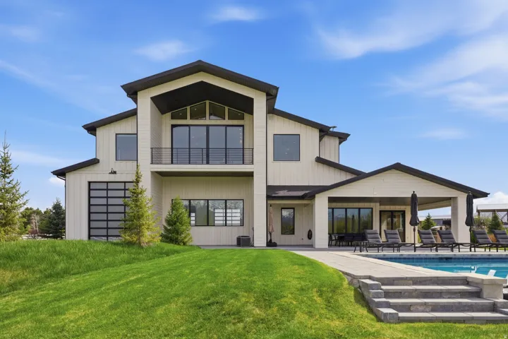 Rear view of property with an outdoor pool, a yard, a balcony, and a patio area