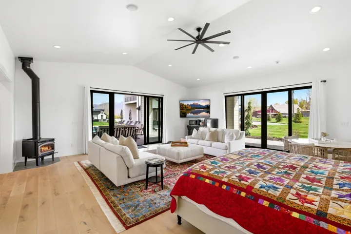 Bedroom featuring access to exterior, light wood finished floors, a wood stove, a ceiling fan, and recessed lighting