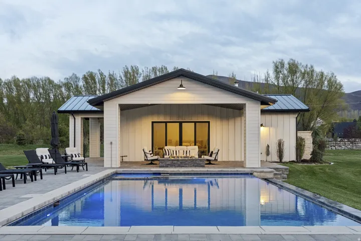 Back of property featuring a standing seam roof, an exterior structure, board and batten siding, and an outdoor pool