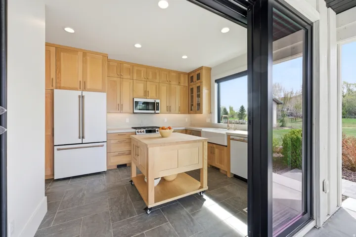 Kitchen featuring light wood finish cabinets, stainless steel appliances, recessed lighting, glass fronted cabinets, and tasteful backsplash