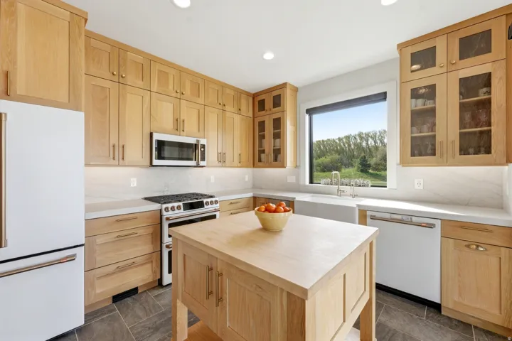 Kitchen with light wood finish cabinetry, white appliances, butcher block counters, tasteful backsplash, and a kitchen island