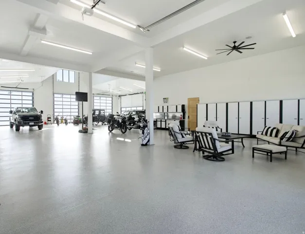 Spacious multi-bay garage with overhead doors, high ceilings, and integrated fluorescent lighting