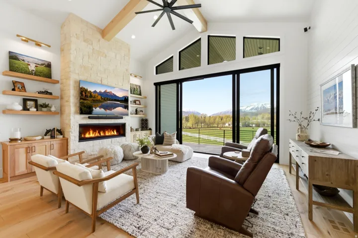 Living area featuring ceiling fan, a fireplace, light wood-type flooring, and lofted ceiling