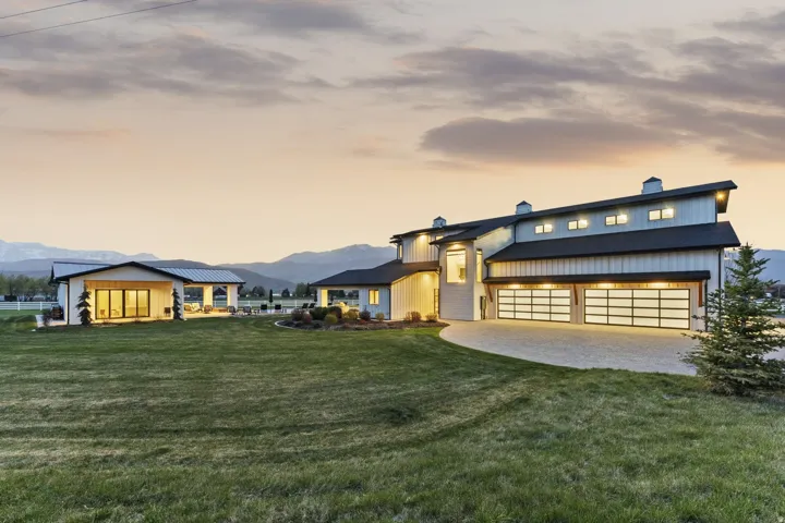View of front of property featuring a chimney, a garage, a mountain view, a lawn, and driveway