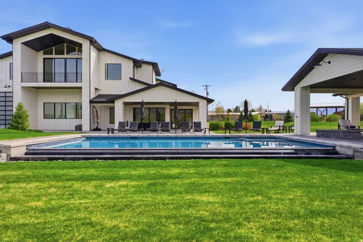 Rear view of house with a yard, an outdoor pool, and a patio area