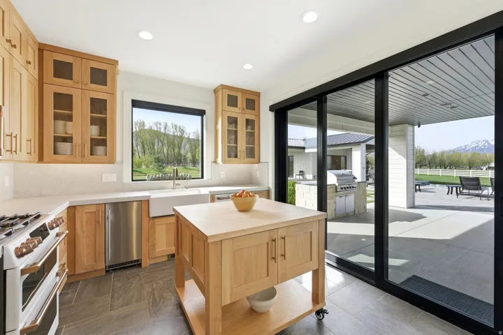Kitchen featuring white range with gas cooktop, light wood finish cabinetry, butcher block countertops, tasteful backsplash, and glass fronted cabinets