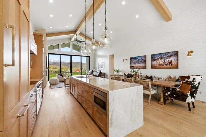Kitchen with open floor plan, light stone counters, a large island, and light wood finished floors