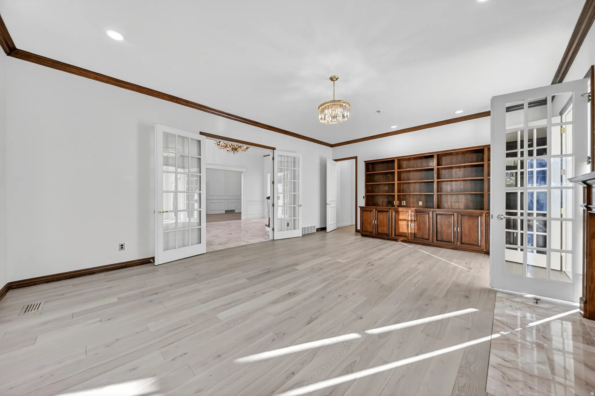 Study with french doors, chandelier, hardwood floors, and crown molding