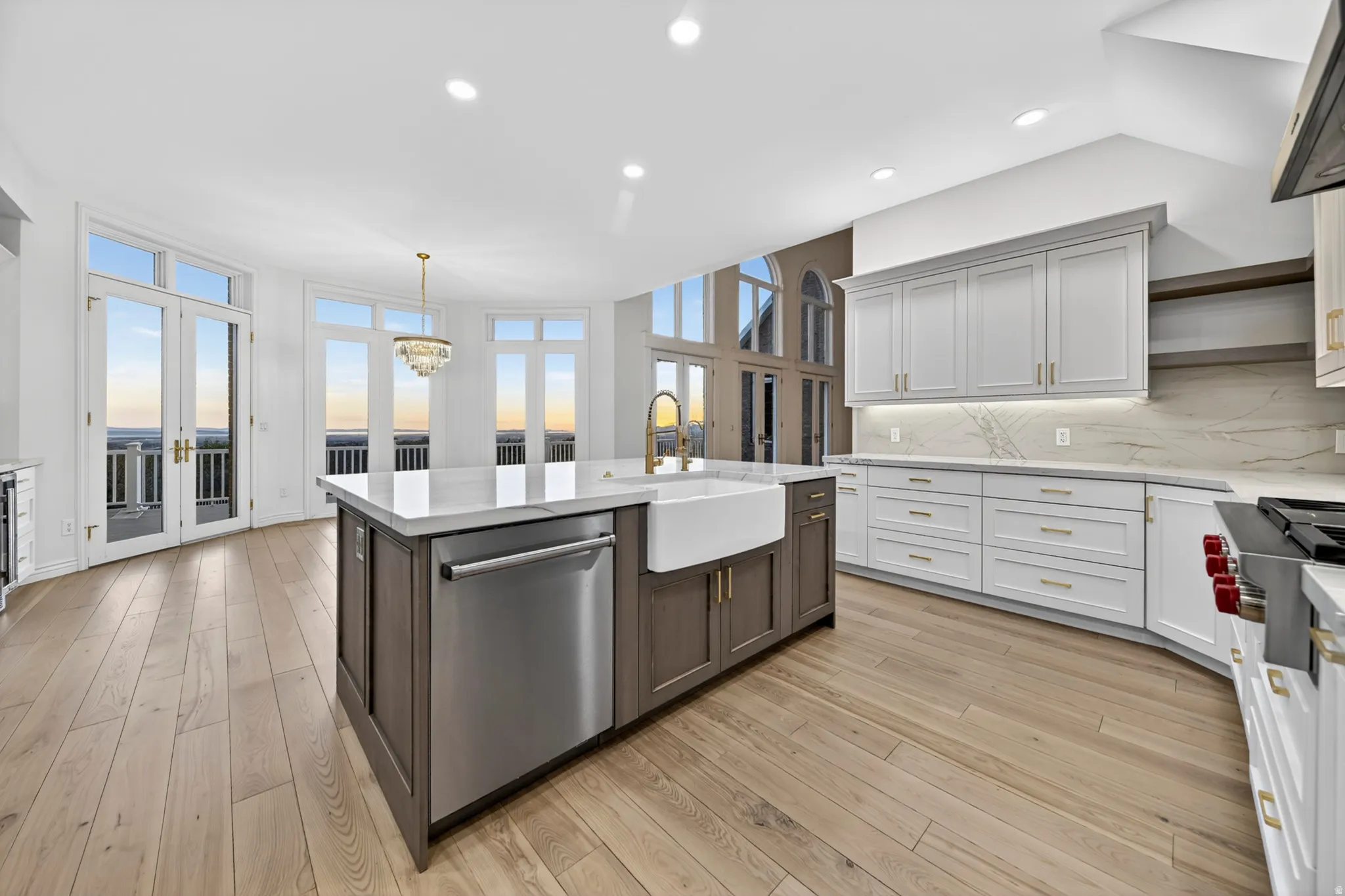 Kitchen featuring two tone cabinetry, stone countertops, Wolf stainless steel appliances, stone backsplash, and hardwood flooring