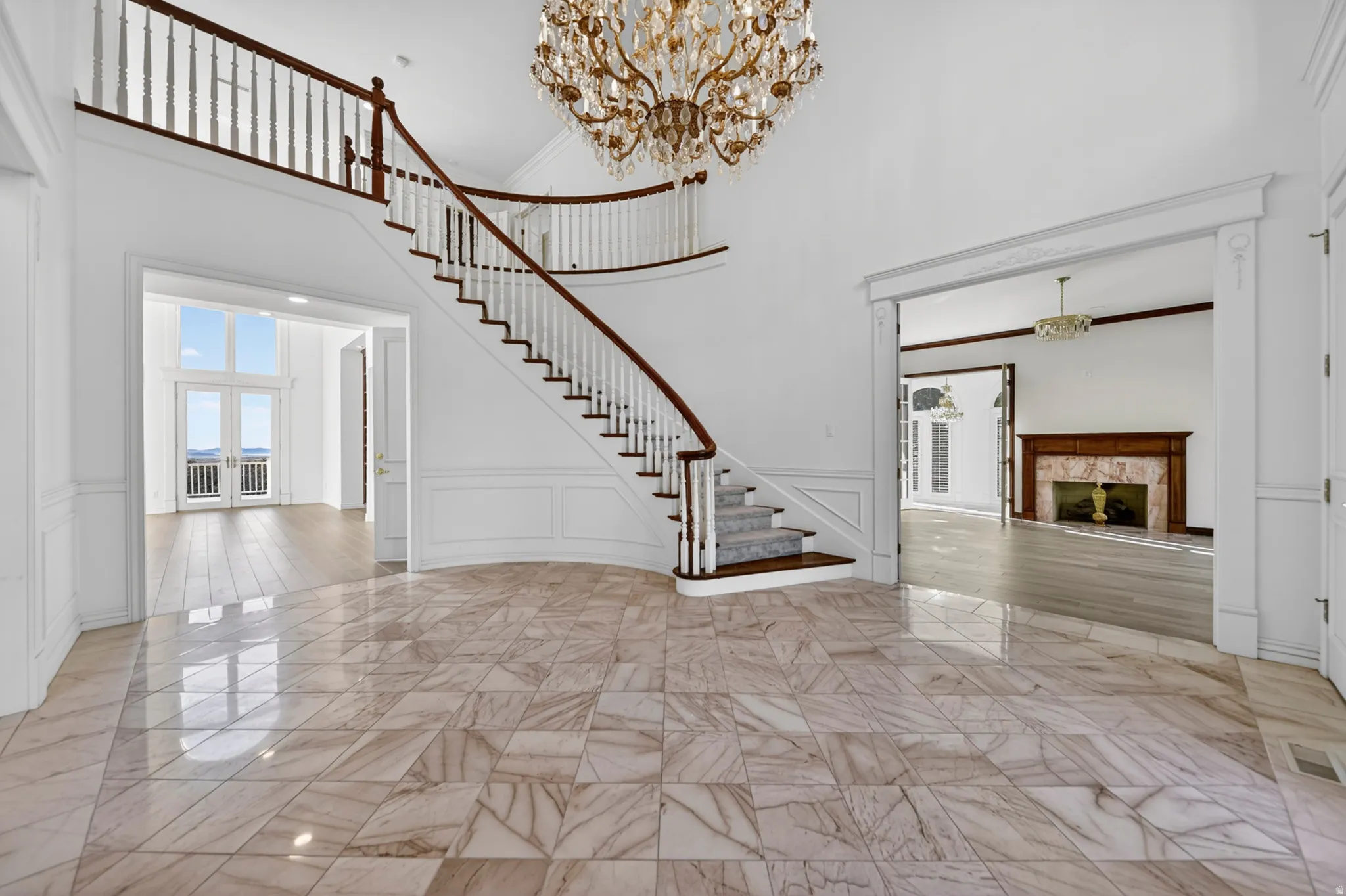 Foyer entrance with a decorative wall, a fireplace, wainscoting, Italian chandelier, and a high ceiling