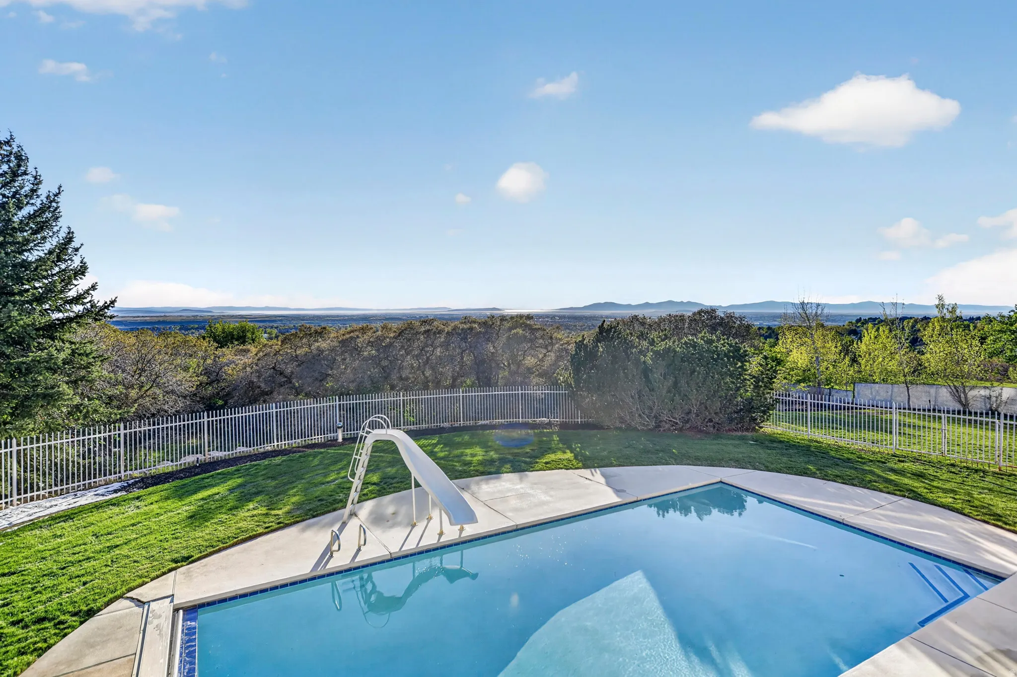 View of swimming pool with a fenced backyard, patio surround, and a water slide