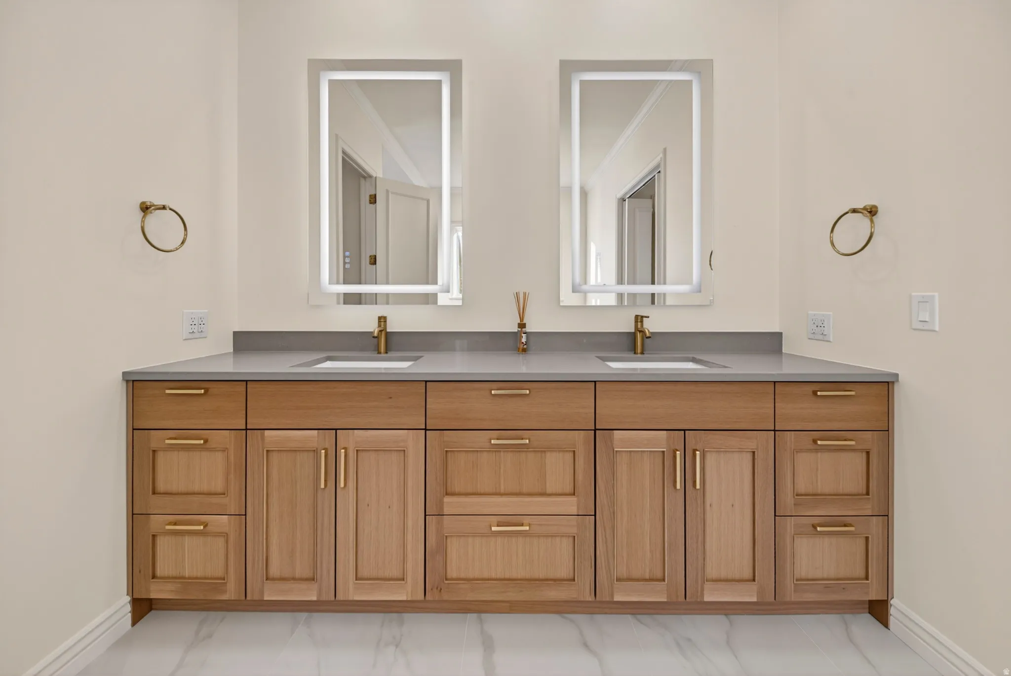 Primary suite bathroom featuring double vanity and light marble finish flooring