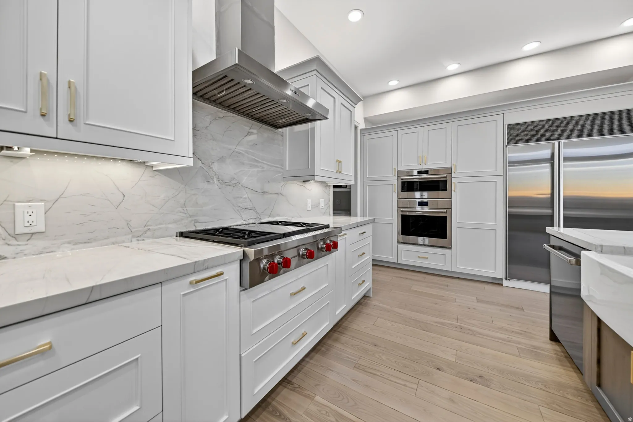 Kitchen featuring stone countertops, Wolf and Sub-Zero stainless steel appliances, hardwood flooring, stone backsplash, and recessed lighting