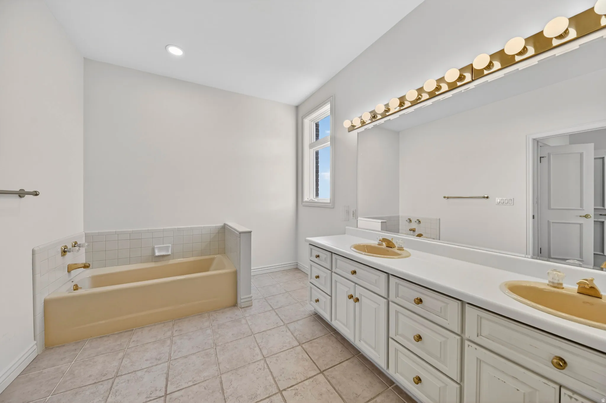 Full bathroom with double vanity, a bath, and light tile floors