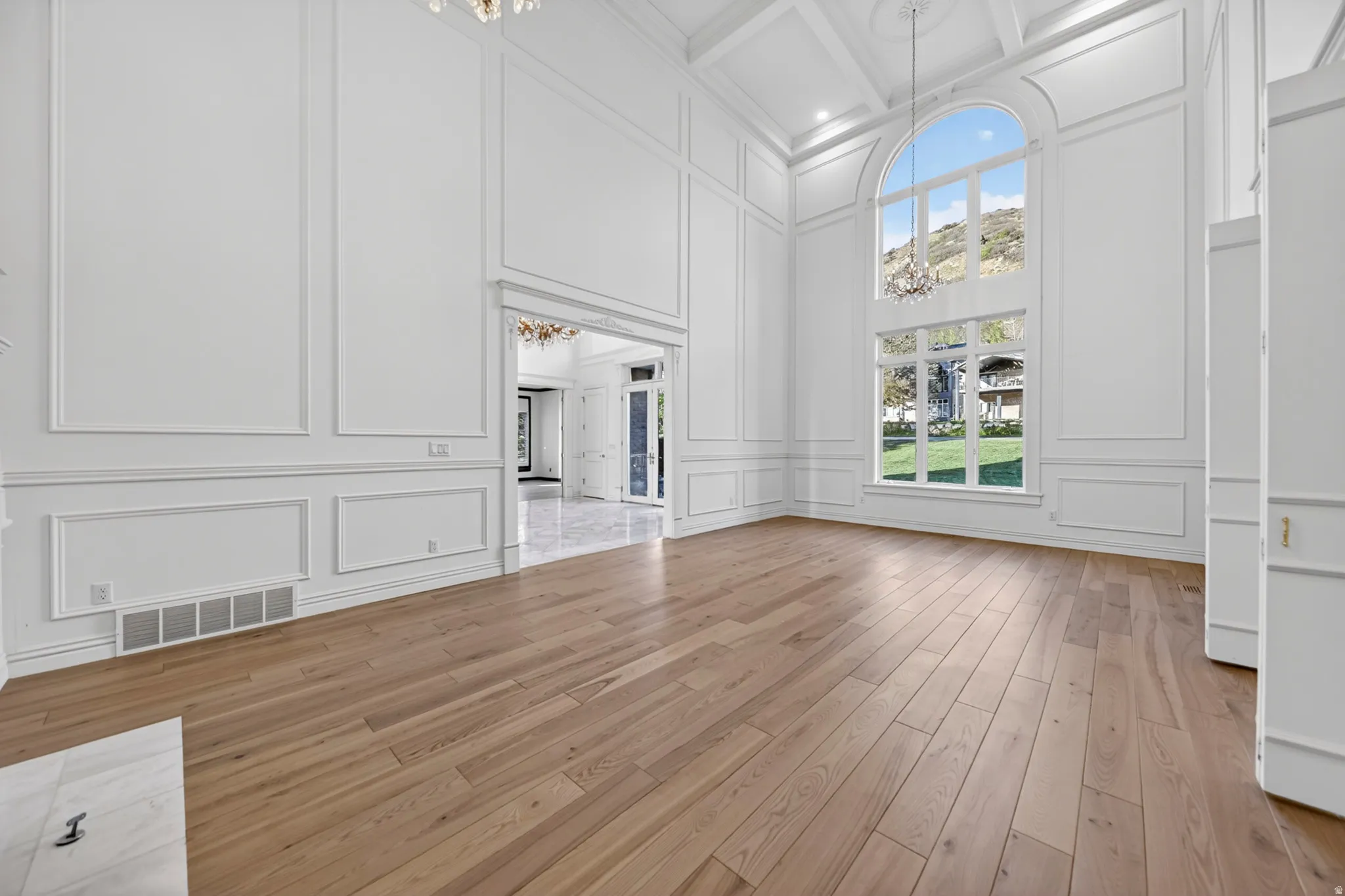 Parlor featuring a decorative wall, a chandeliers, hardwood flooring, and coffered ceiling