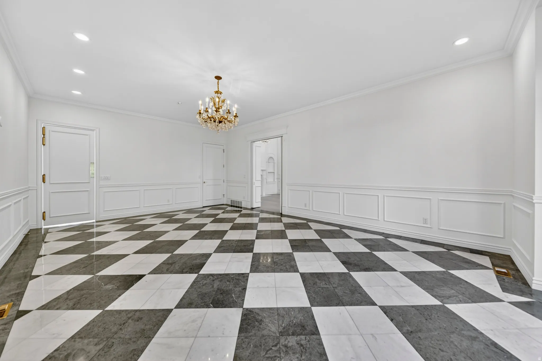 Dining room featuring a decorative wall, wainscoting, chandelier and recessed lighting, ornamental molding, and marble floors