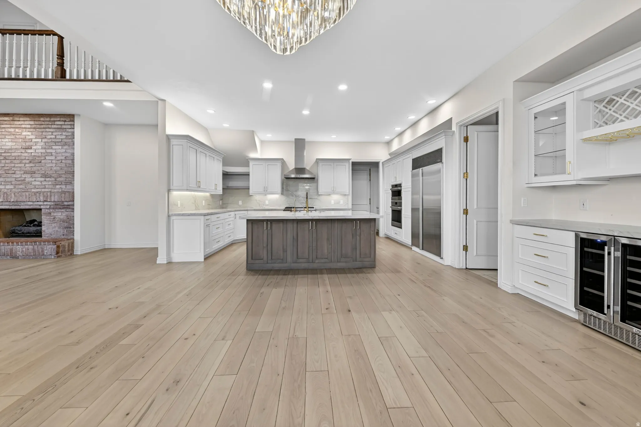 Kitchen featuring a kitchen island with sink, a brick fireplace, open shelves, glass fronted cabinets, and stone backsplash