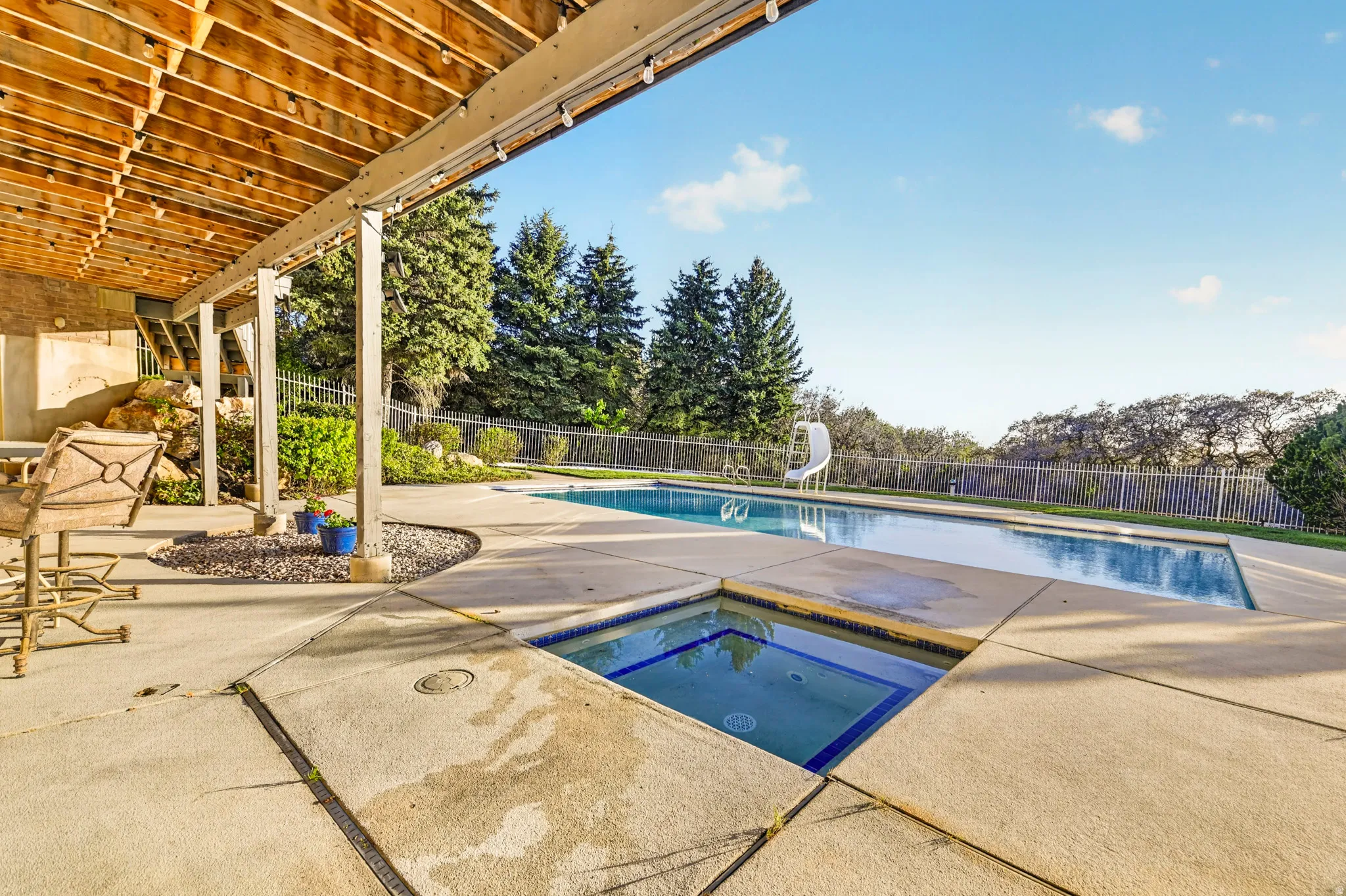 View of pool featuring a fenced backyard, an in-ground hot tub, patio surround, and a water slide