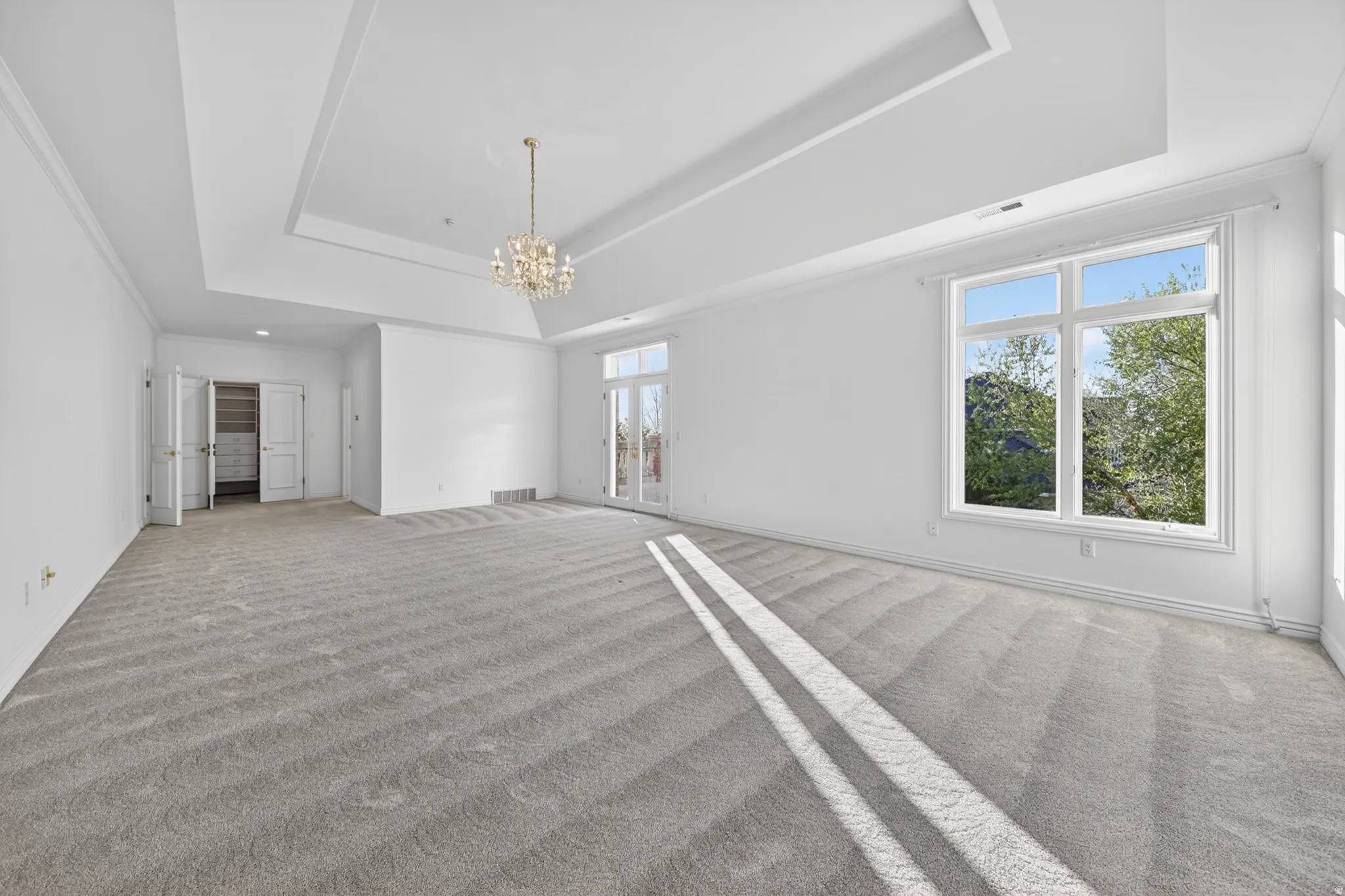 Bedroom with ornamental molding, a chandelier, and light carpet