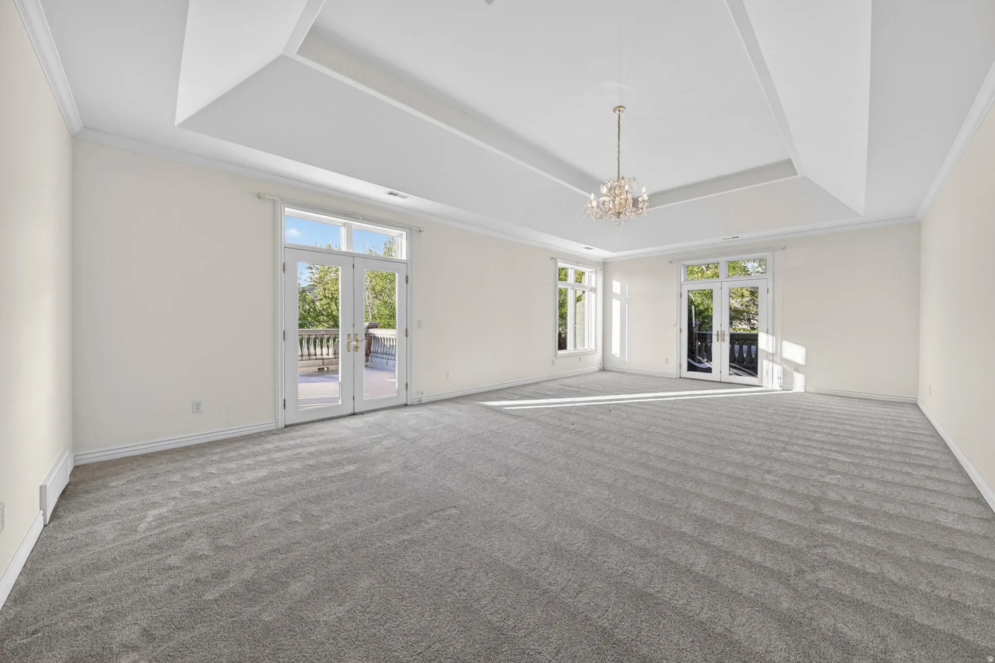 Bedroom with french doors, balconies, ornamental molding, carpet, and chandelier