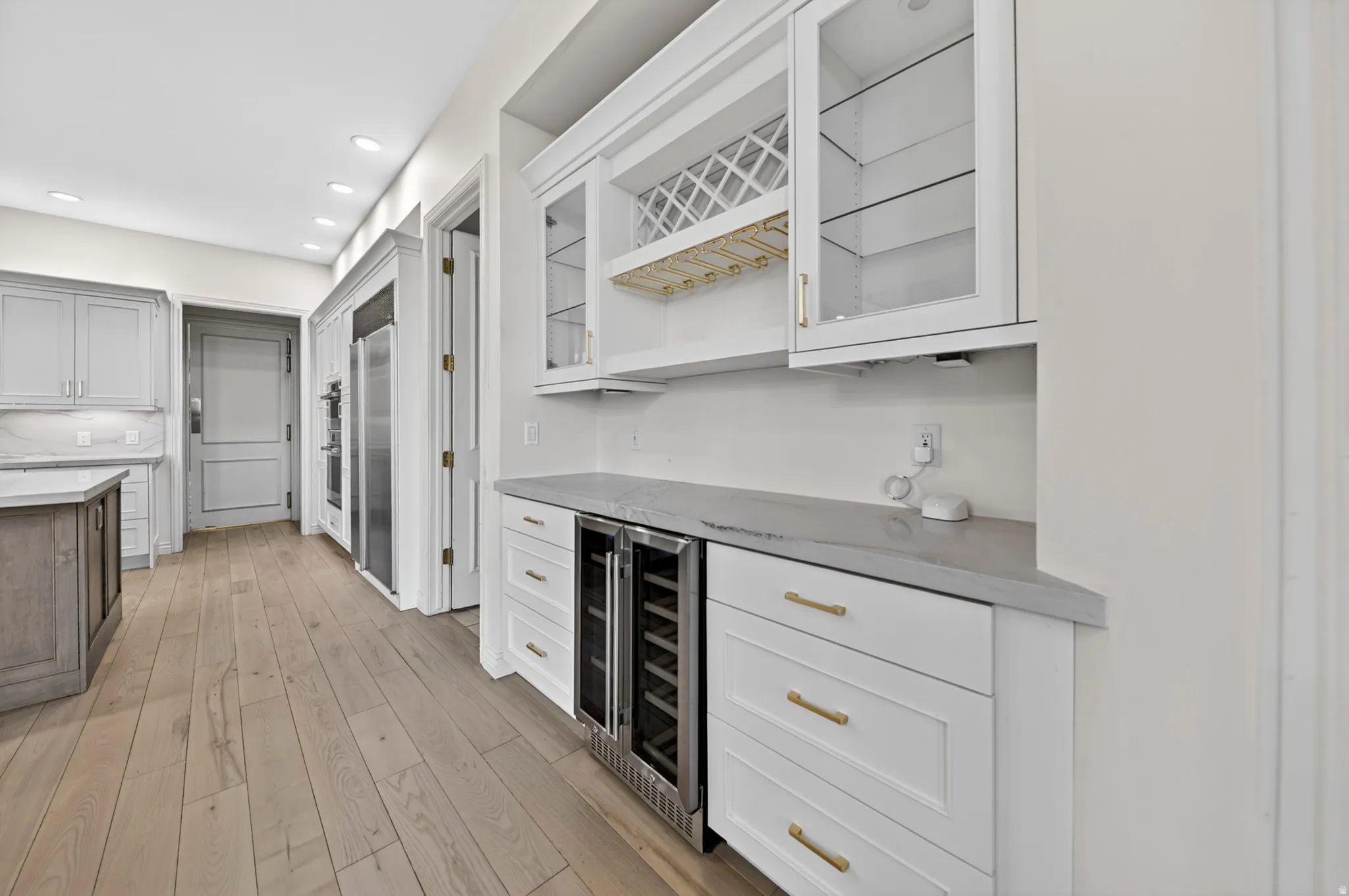 Indoor dry bar featuring hardwood flooring, glass insert cabinets, stone counters, dual tone cabinetry, and wine cooler