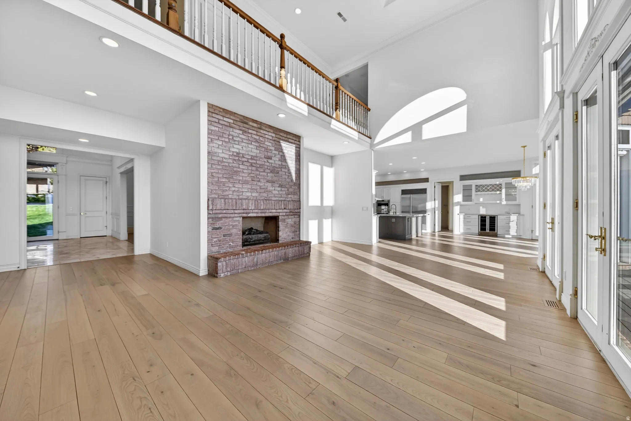 Unfurnished living room featuring a brick fireplace, ornamental molding, hardwood flooring, a high ceiling, and recessed lighting