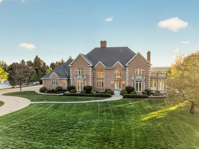Colonial house featuring a front yard, a chimney, brick siding, and a shingled roof