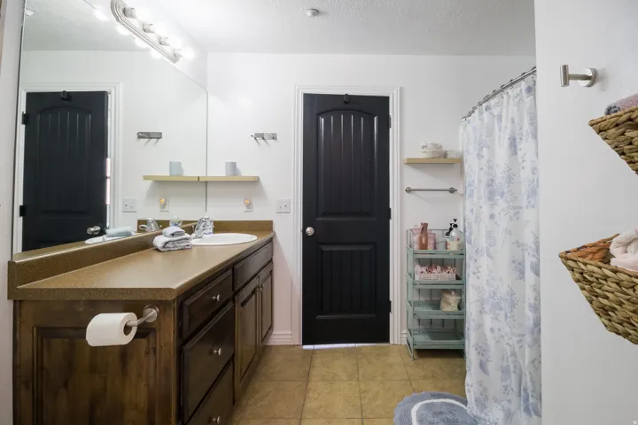 Bathroom with vanity, a textured ceiling, light tile patterned floors, and curtained shower