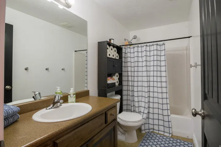 Bathroom featuring vanity, shower / tub combo, a textured ceiling, and light tile patterned flooring