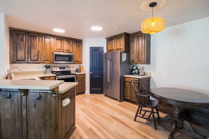 Kitchen with light countertops, stainless steel appliances, a peninsula, light wood-style floors, and pendant lighting
