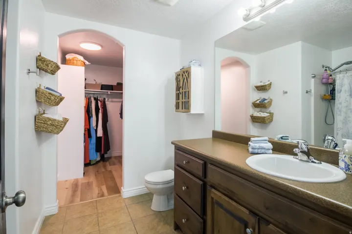 Full bath featuring light tile patterned flooring, vanity, a shower with curtain, a textured ceiling, and a spacious closet