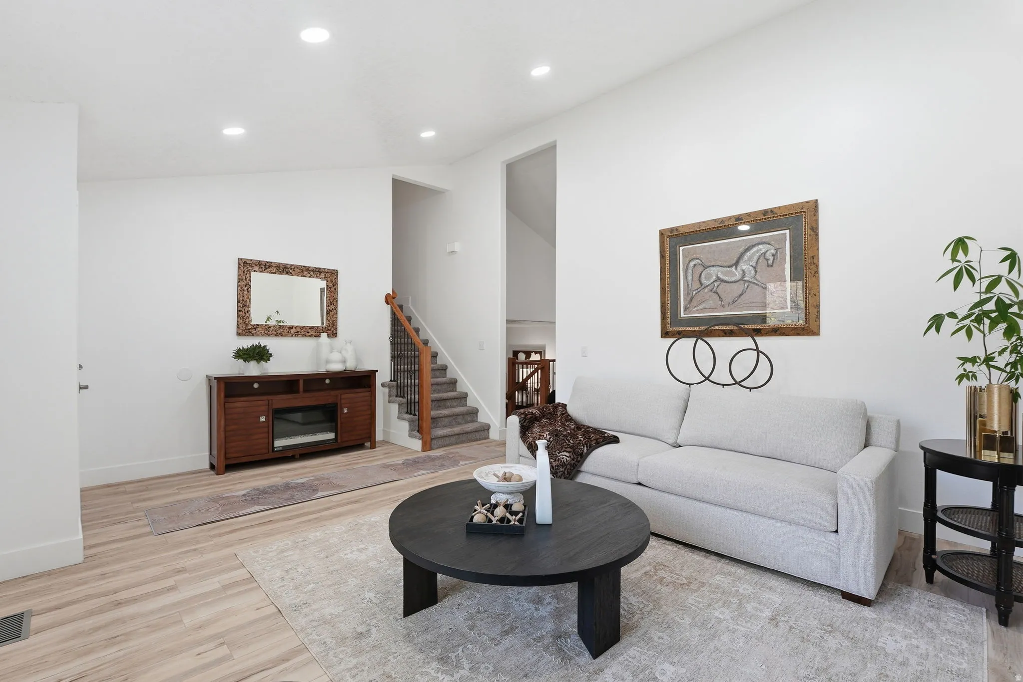 Living area with vaulted ceiling, light wood-style flooring, and recessed lighting