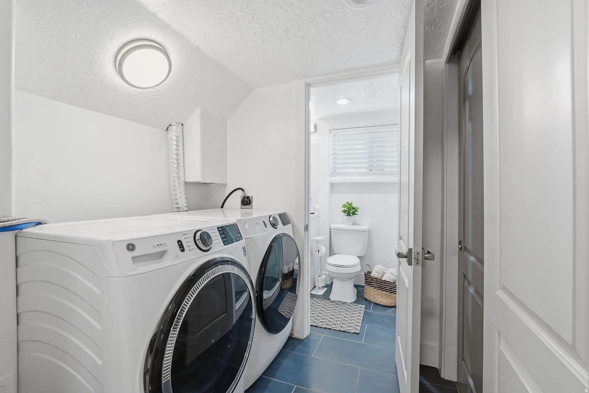 Laundry area featuring dark tile patterned flooring and washer and dryer