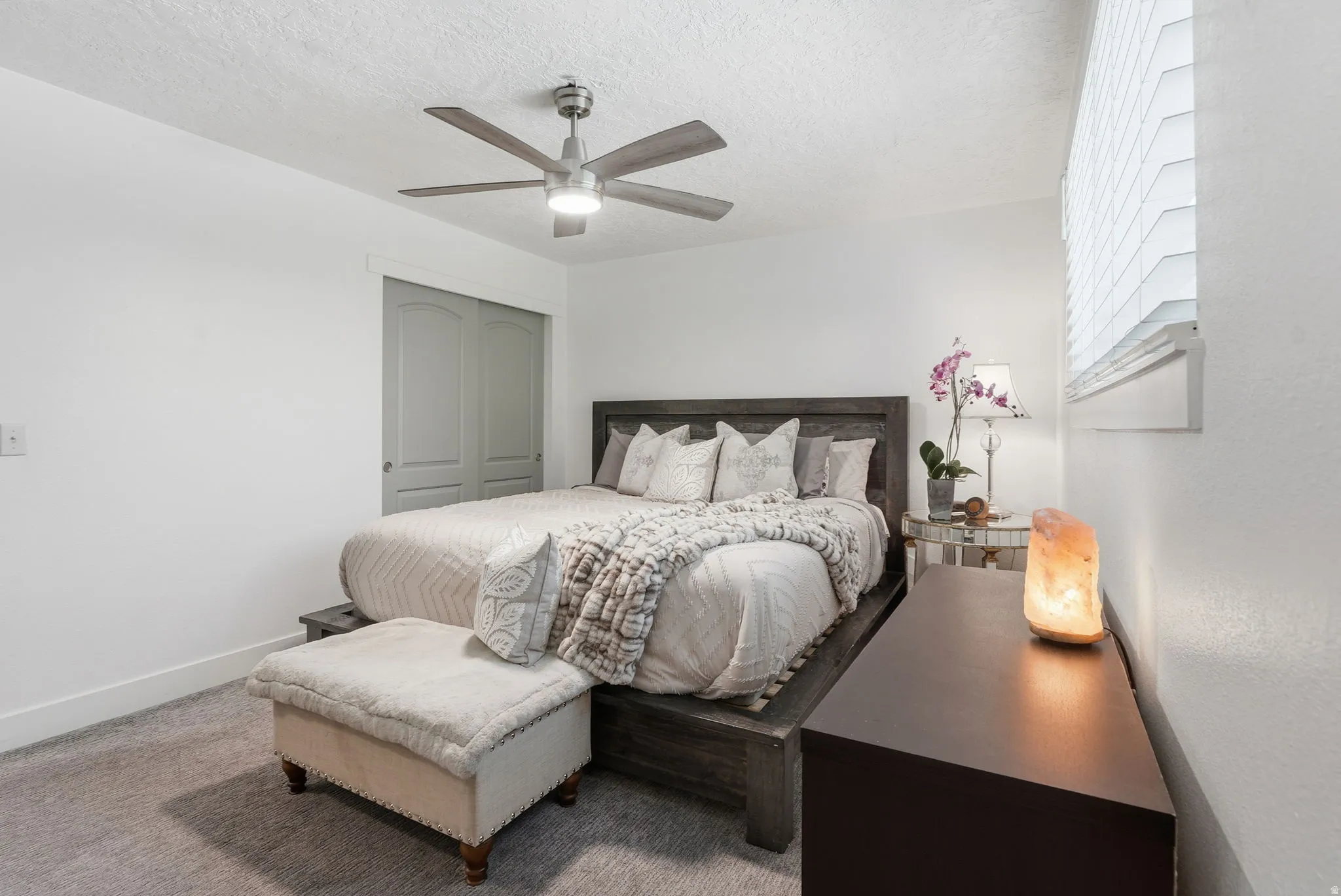 Bedroom featuring ceiling fan, carpet floors, a textured ceiling, and a closet