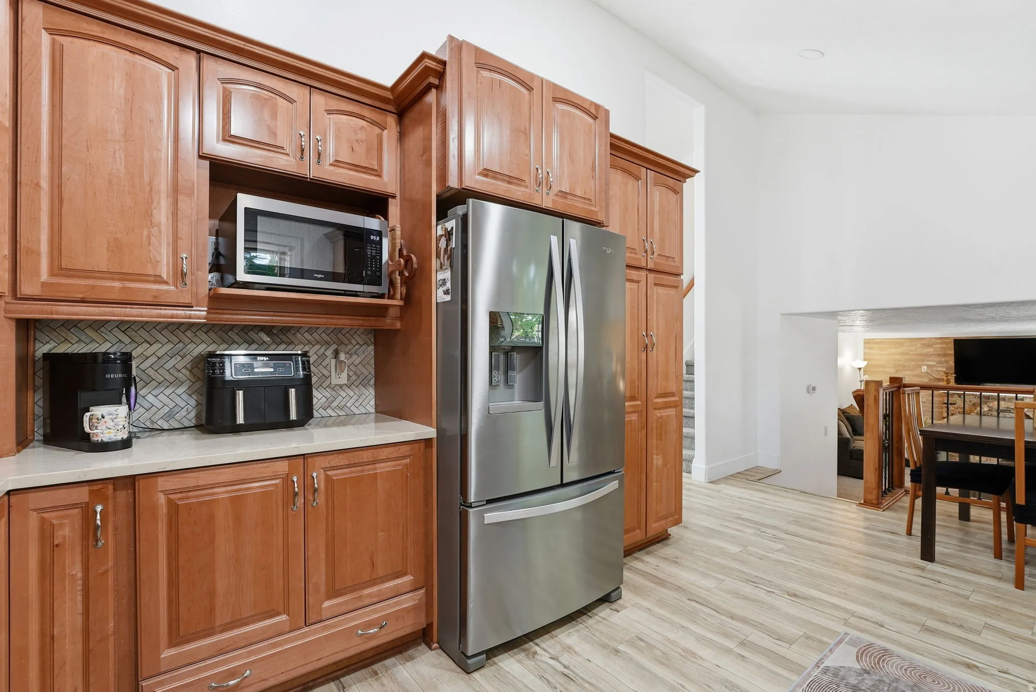 Kitchen featuring stainless steel appliances, decorative backsplash, light wood finished floors, and wood finish cabinets