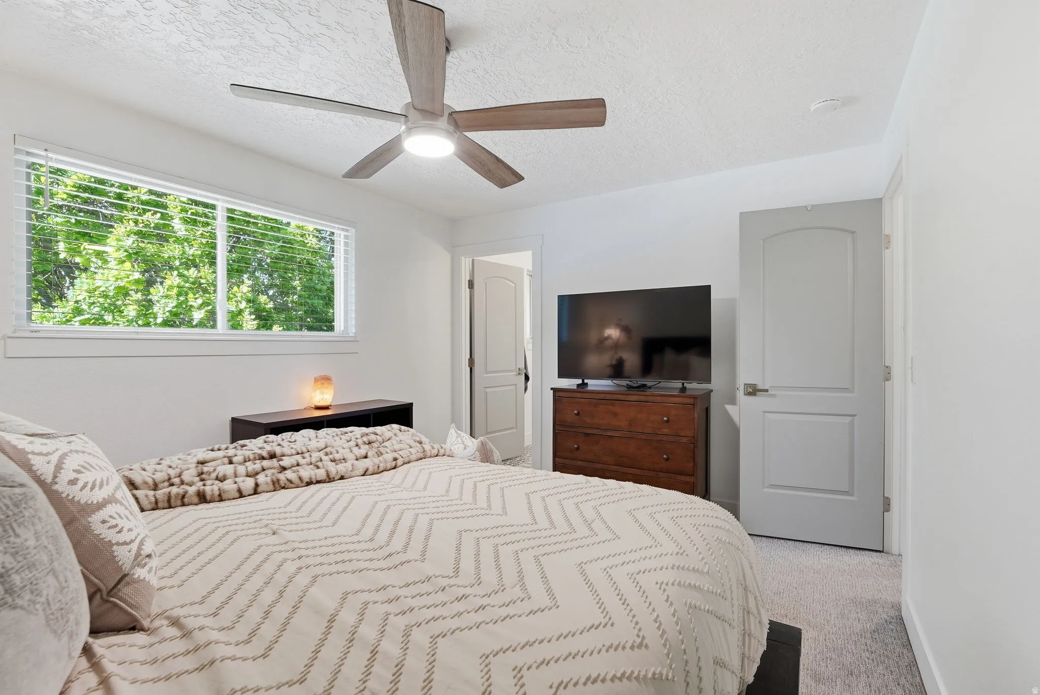 Bedroom with light colored carpet, a textured ceiling, and ceiling fan