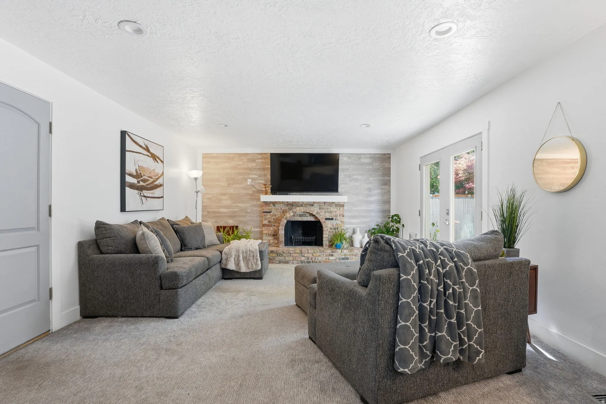 Living room featuring carpet, a textured ceiling, a brick fireplace, and an accent wall