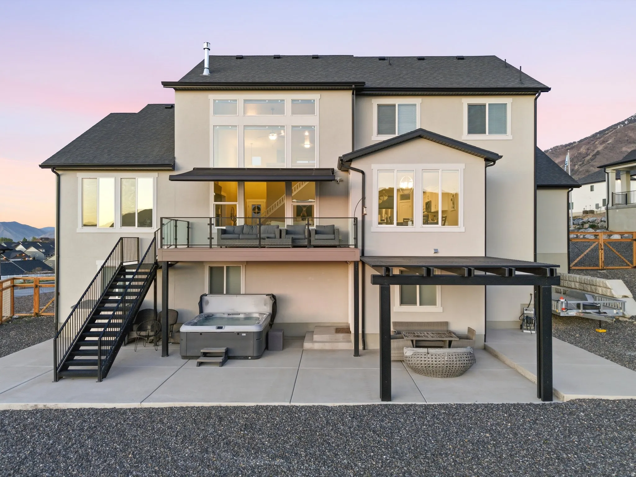 Back of property at dusk with a patio area, stucco siding, a balcony, and a mountain view