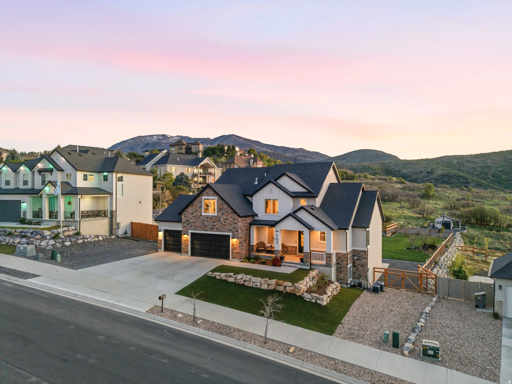 Modern farmhouse style home featuring a gate, covered porch, driveway, and stone siding