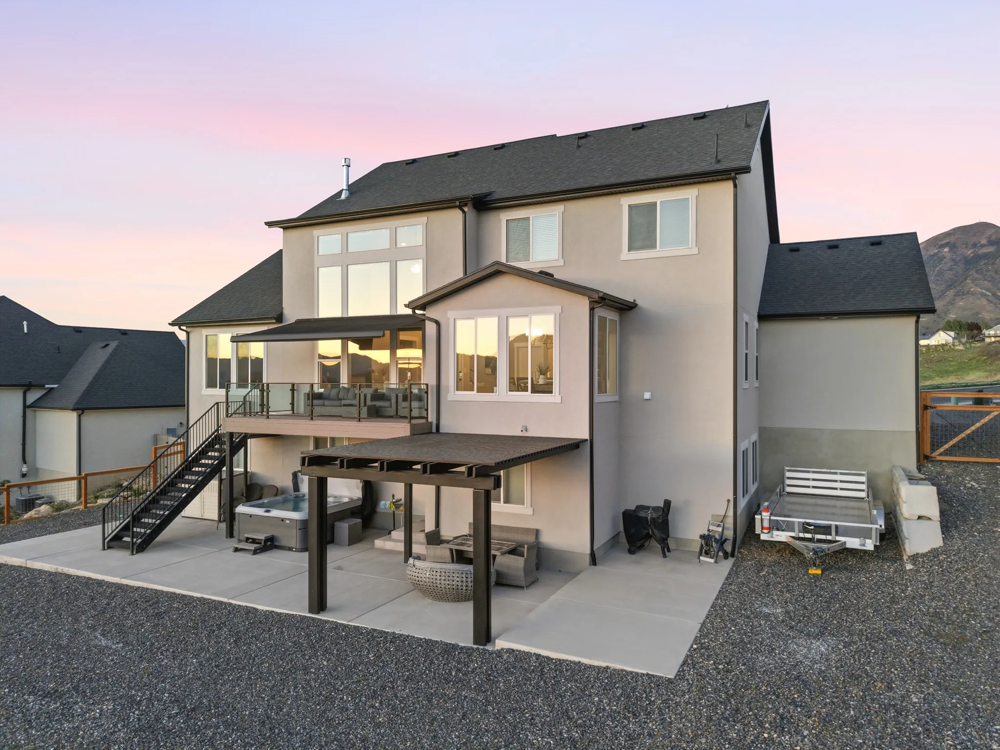 Back of property at dusk with a patio, roof with shingles, an outdoor hangout area, and stucco siding