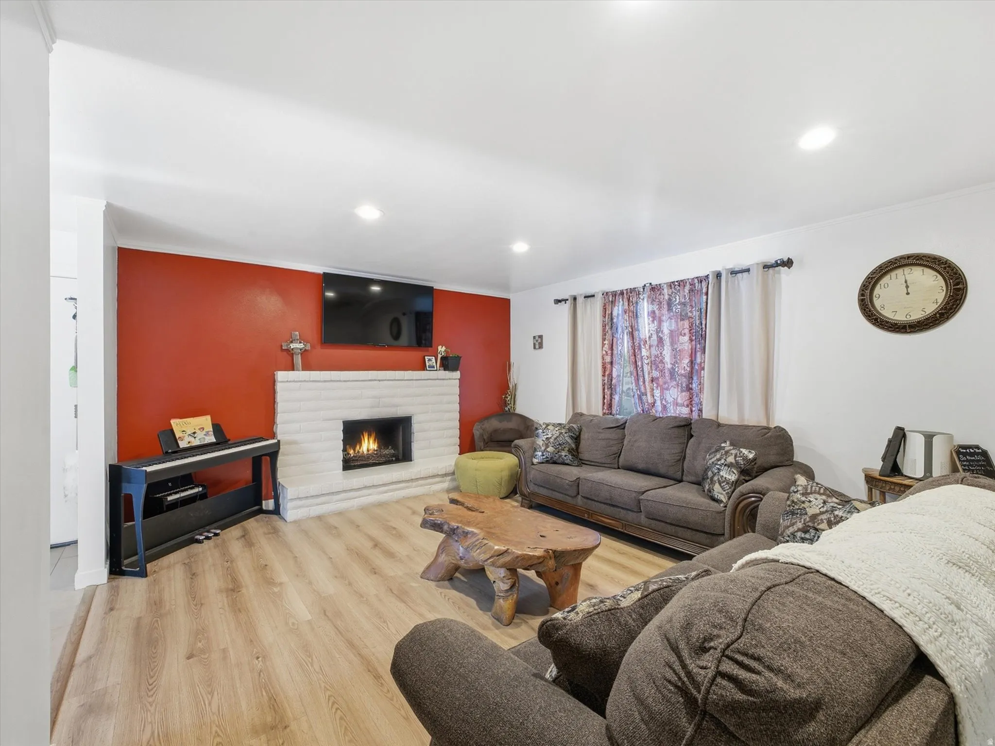 Living area featuring light wood-style flooring, a fireplace, recessed lighting, and crown molding