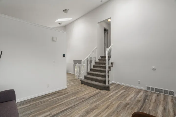 Stairs with wood finished floors, a skylight, and a high ceiling