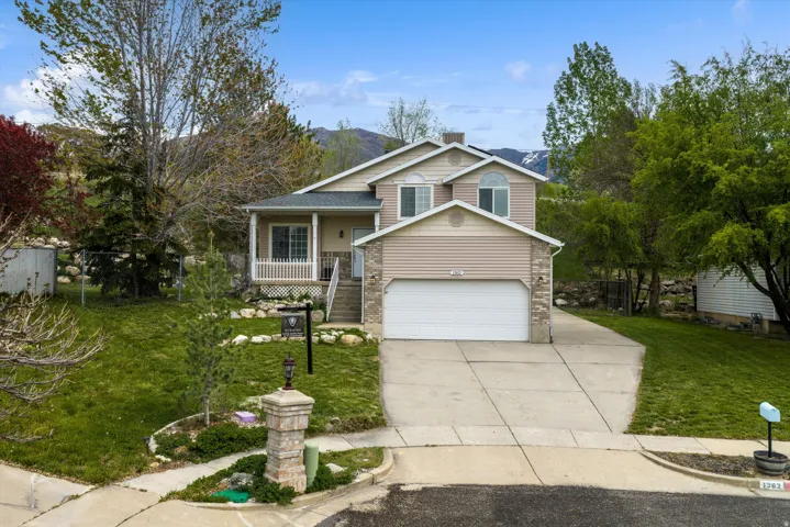 Tri-level home with a front lawn, driveway, covered porch, a garage, and a mountain view