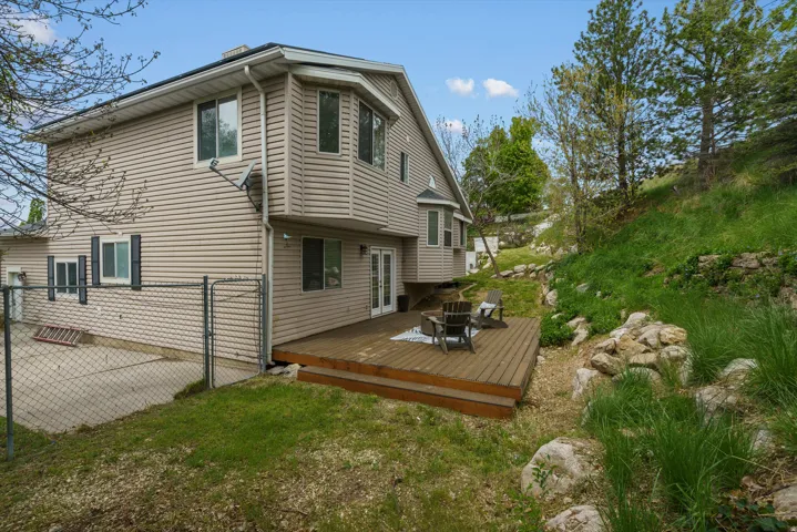 Rear view of house featuring a wooden deck, a gate, and a lawn