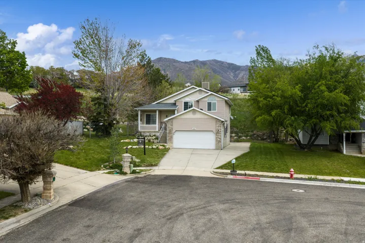 View of front facade featuring a front lawn, driveway, a mountain view, and an attached garage