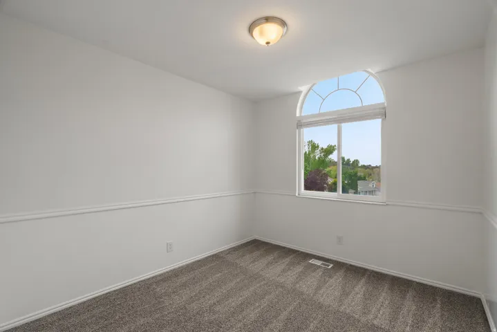 Spare room featuring dark carpet and baseboards